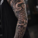 Detailed tattoo background filler sleeve with smoke shading and geometric black and grey transitions